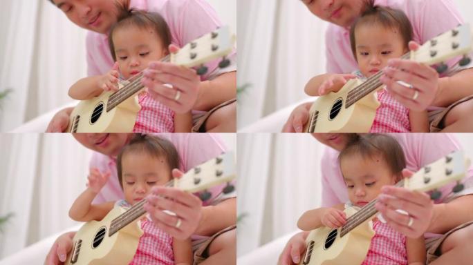 两岁的女儿和爸爸在沙发上弹吉他。