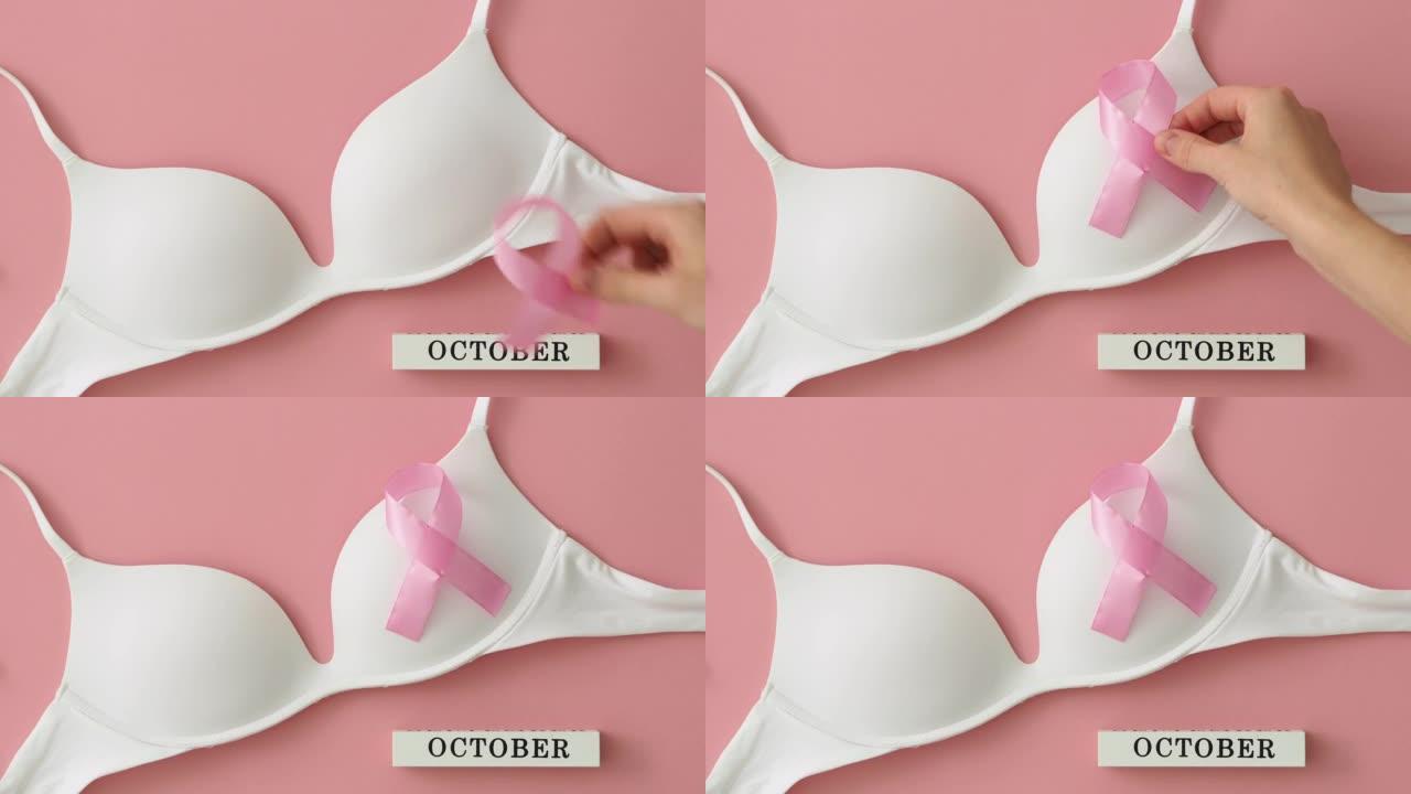 粉色背景乳腺癌宣传月。女人的手放一条粉红色的丝带-白色胸罩上的蝴蝶结。希望和恢复的象征。世界癌症日概