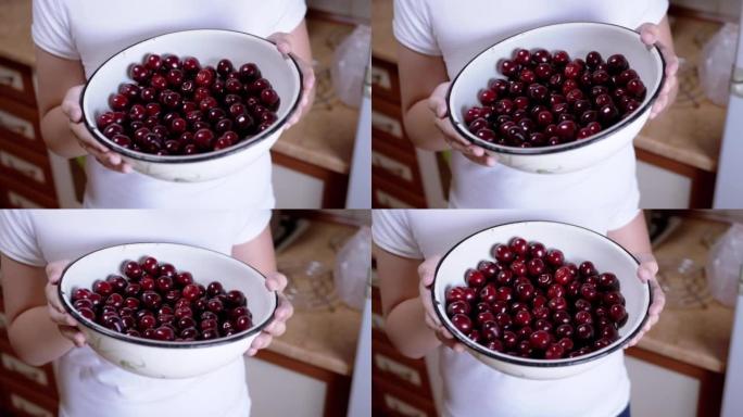 站在厨房里的孩子手里拿着满满的红樱桃。4K