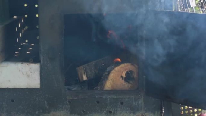 男子将柴火扔进烤箱或烧烤炉的火中