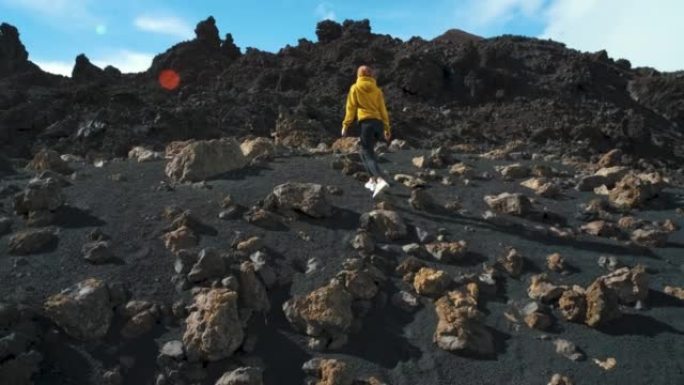 女旅行者在特内里费岛泰德国家公园的钦耶罗火山周围的熔岩田野中漫步。去任何地方。另一个星球的表面。慢动