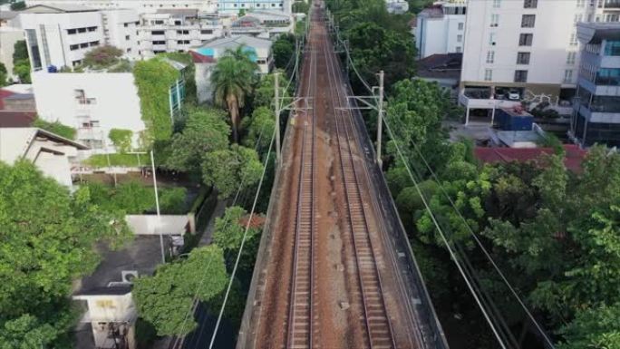 空双轨铁路线穿过城镇的鸟瞰图。向前飞行的无人机