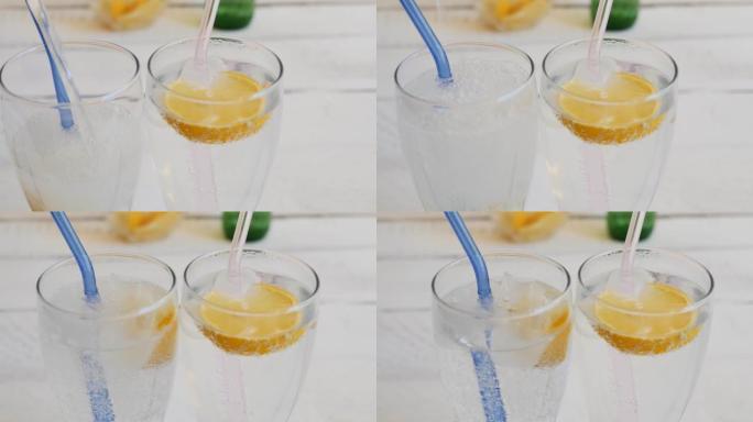 将清爽的碳酸饮料倒入两个装有冰块和柠檬片的玻璃杯中。玻璃可重复使用的吸管插入眼镜中。柠檬味苏打水。多