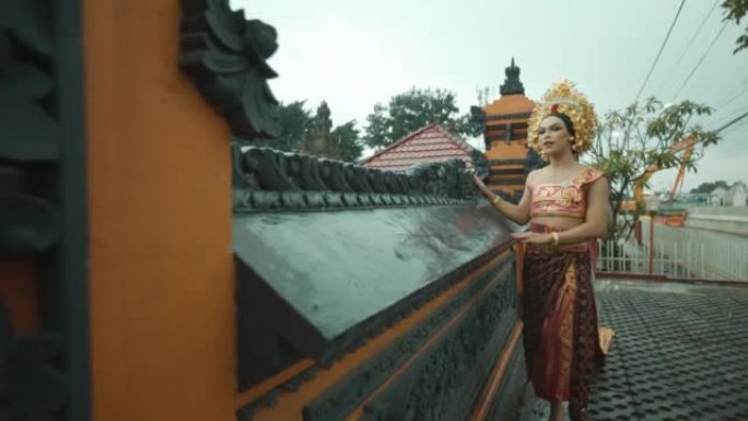 一名穿着红色金色服装的巴厘岛女孩走向寺庙祈祷