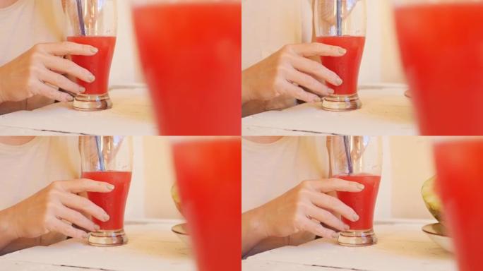 一名妇女通过玻璃杯可重复使用的吸管从玻璃杯中喝红西瓜饮料。特写，多莉拍摄，可重复使用的菜肴和健康饮食