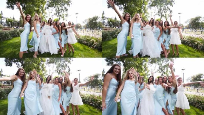 美丽的新娘和她漂亮的新娘穿着同样的淡蓝色连衣裙，在公园里欢呼挥手。穿着白色礼服派对的长而通风的新娘面