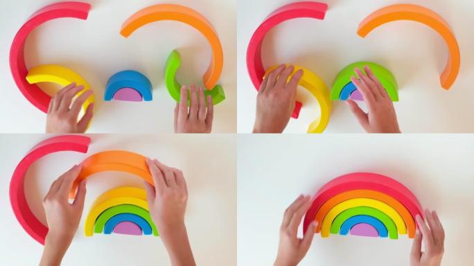 孩子们的手在白色桌子背景上玩木制玩具彩虹。手眼协调发展。集中。早期教育理念。感官游戏。精细的运动技能