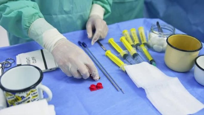 医务人员的手戴着乳胶手套触摸桌子上的工具。协助准备干细胞操作的仪器和材料。特写。