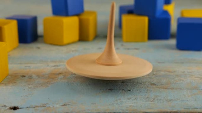 Peg玩具或whirligig在儿童玩具块的背景下在老式木板上旋转。