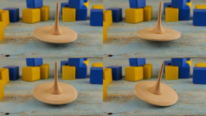 Peg玩具或whirligig在儿童玩具块的背景下在老式木板上旋转。