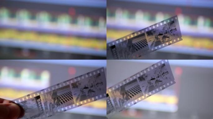 在监视器屏幕上的现代数字视频编辑软件正面的特写镜头中，男性手持旧胶片，显示了摄影和视频编辑剪辑的技术