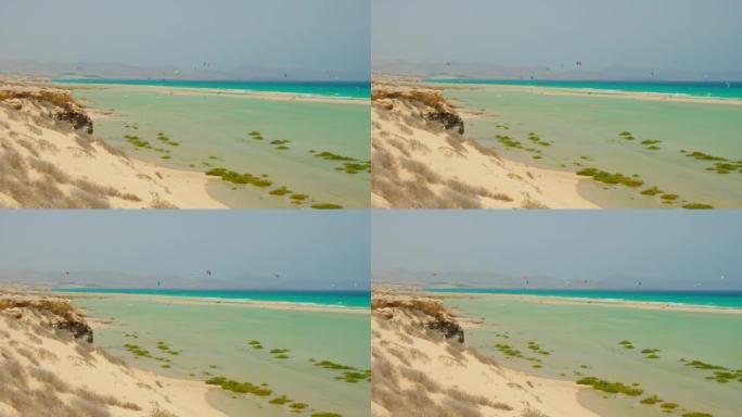 在野生白色沙滩的蓝天前降落伞。游客在天堂岛享受滑翔伞体验。无法识别的人飞行，滑翔伞体验
