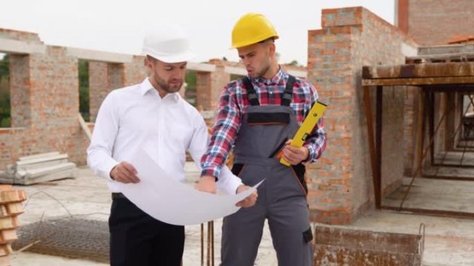 Two construction workers look at an architectural 