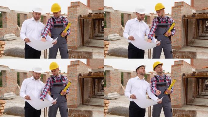 Two construction workers look at an architectural 