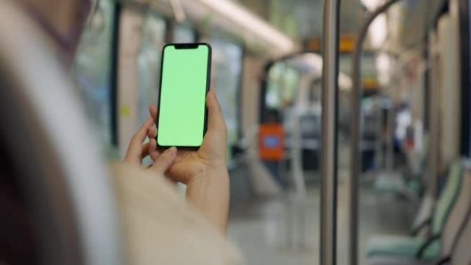 亚洲妇女在火车上使用带有绿屏的智能手机