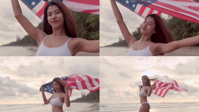 年轻的亚洲妇女在海滩享受时间，在夏天的海滩上，独立纪念日7月4日，在日落的天空上，持有和挥舞美国国旗