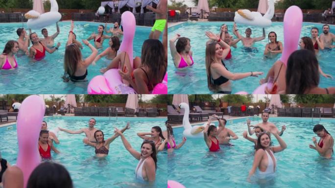 朋友在私人别墅游泳池举行夜间泳池派对。穿着泳装的快乐年轻人在豪华度假胜地泼水，与漂浮物和充气床垫跳舞