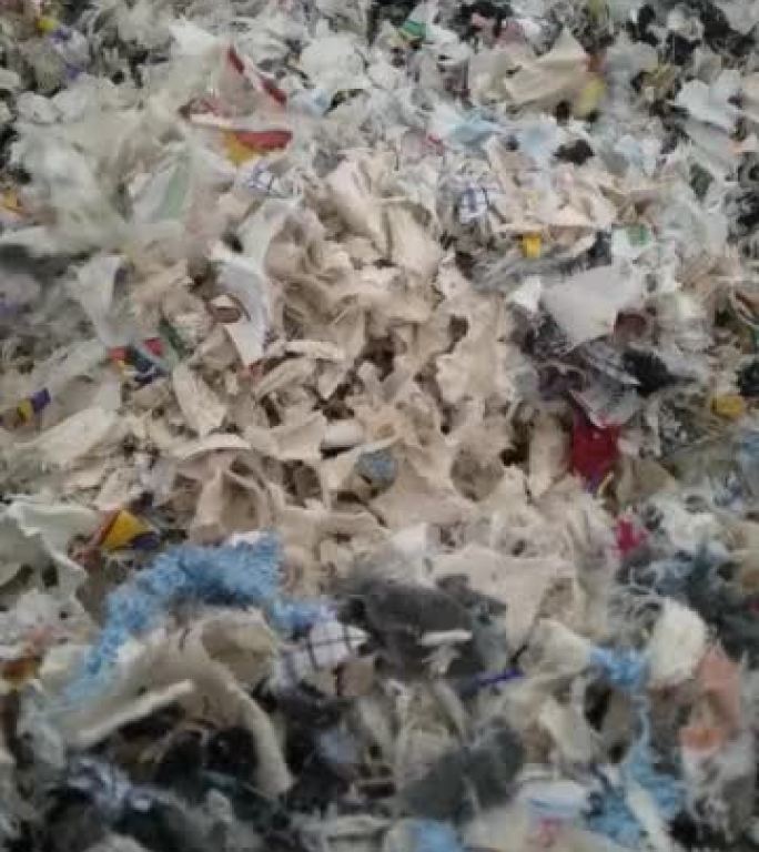 切碎的纺织品残渣掉到一个大袋子里。60fps概念回收行业。特写