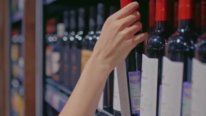 特写镜头，瓶装酒在超市货架上，酒精饮料部门。女人的手从架子上拿了一瓶酒，买了一杯酒精饮料。4k，普洛