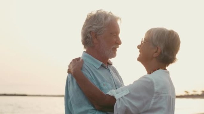 几个老成熟的人一起跳舞，在沙滩上玩得开心，享受和生活的时刻。恋爱中的老年人看起来很开心的肖像。