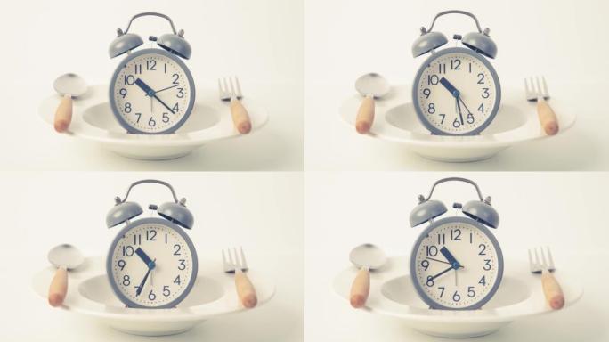 减肥时间，间歇性禁食饮食控制或饮食时间概念，白色背景上带有盘子和勺子装饰的闹钟