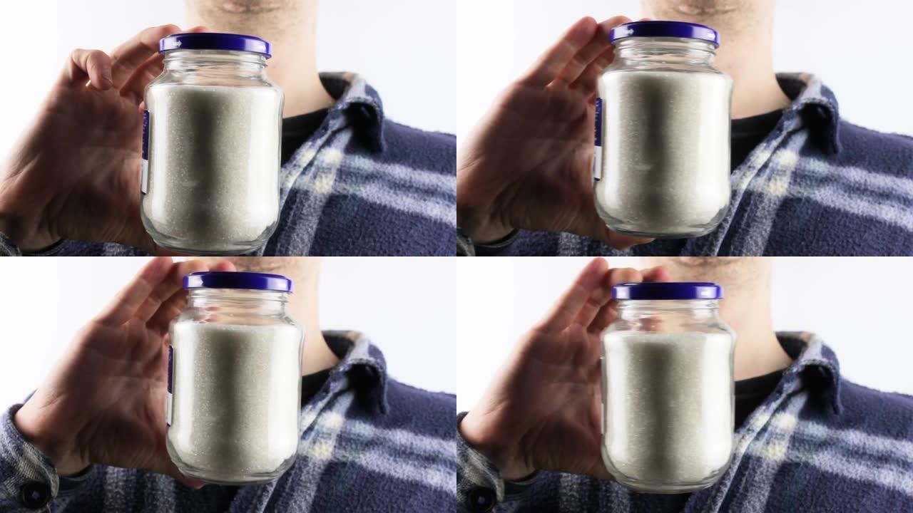 A man holds a glass jar with sugar crumbs. Sugar, 