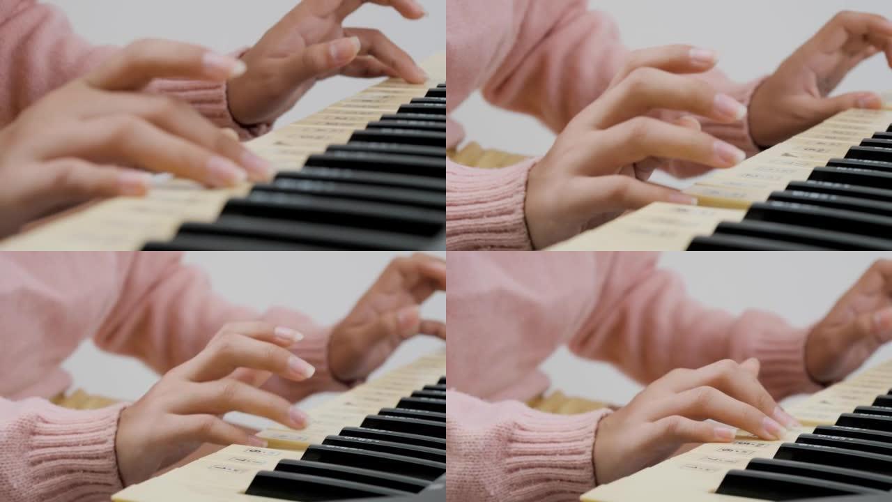 女孩穿着粉红色的毛衣，对着白色的墙壁弹电子钢琴。身体部位。