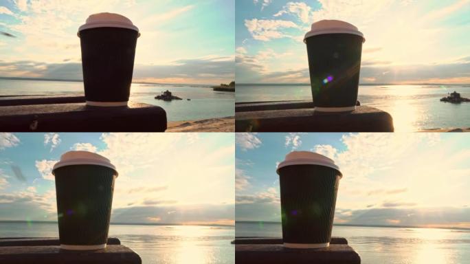日落时在路堤长椅上的纸杯里喝咖啡