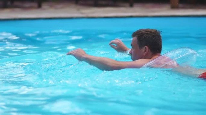 一个男人在一个有充气圈的游泳池里游泳。