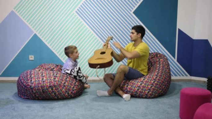 男生在男音乐老师的帮助下学习如何弹奏原声吉他