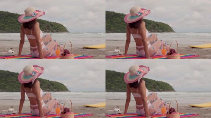 穿着比基尼性感的年轻亚洲女性坐在沙滩上放松夏天，她放松在沙滩上