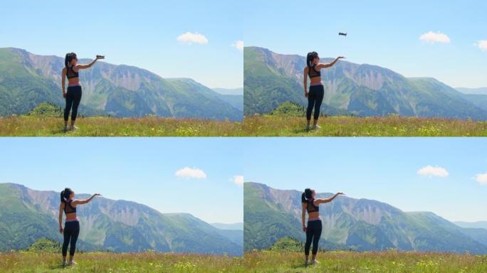 空中特写镜头漂亮的白人妇女手握无人机在风景优美的山区起飞。航空摄影和四轴飞行器旅行