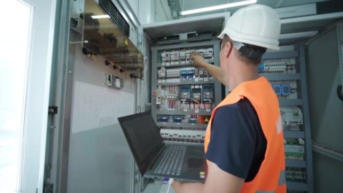 电气工程师在主配电系统室中检查负载中心机柜或消费单元前部的电流电压和过载，以进行维护。