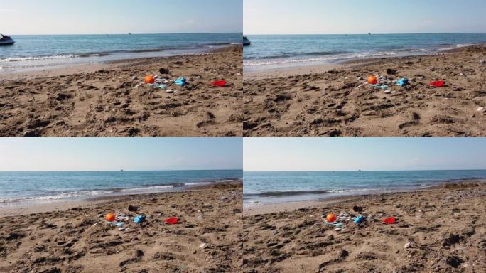 孩子们的塑料玩具散落在沙滩上。废弃的水桶和铲子在沙子里。