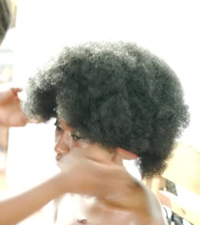一名年轻女子在沙龙里调整了她的非洲假发
