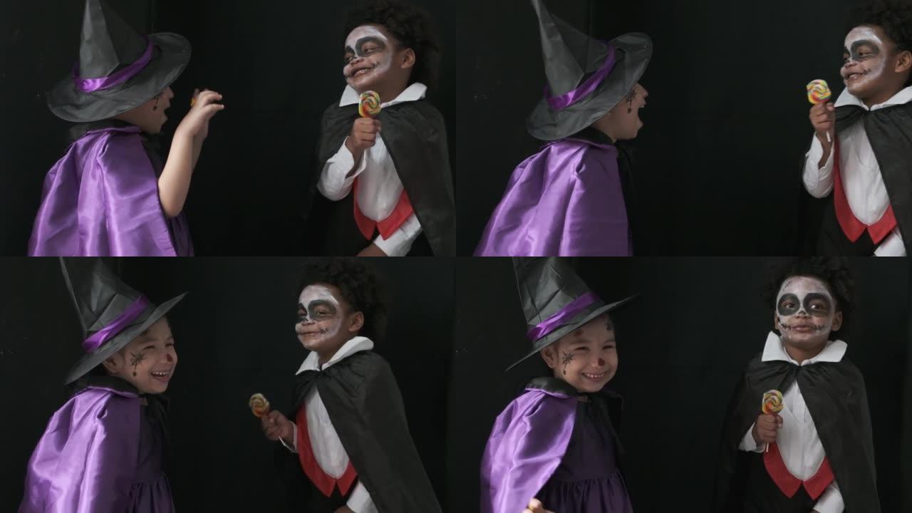 可爱的儿童女孩和黑色皮肤男孩在女巫和德古拉恐怖万圣节服装愉快地玩耍和戏弄对方与黑色背景，慢动作拍摄。