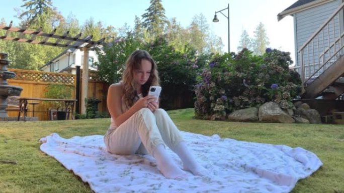 一个十几岁的女孩坐在大自然中，但没有把目光从电话上移开。她坐在社交网络Facebook Instag