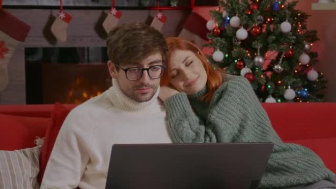 年轻幸福的夫妇在圣诞节假期使用笔记本电脑。