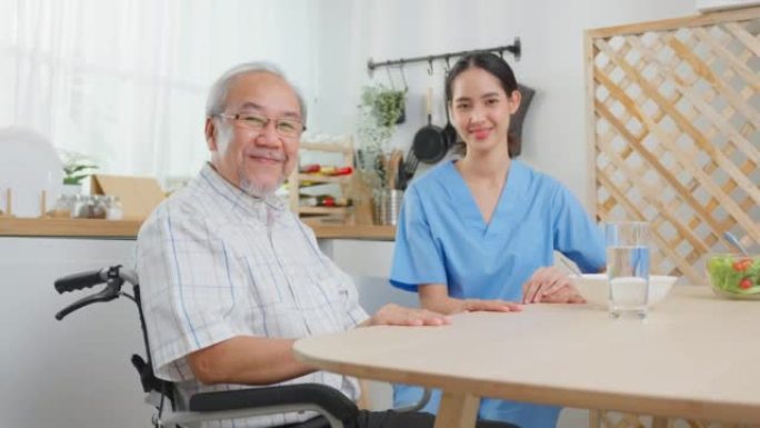 亚洲护理员护士的肖像坐在轮椅上照顾高级男性。有吸引力的专业护理妇女支持老年成熟的祖父在养老院护理和微