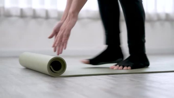 年轻人在家锻炼前铺瑜伽垫。