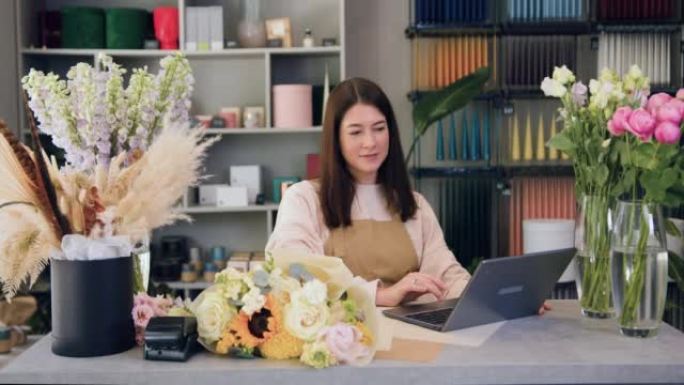 Florist woman using laptop. Flower shop owner wari