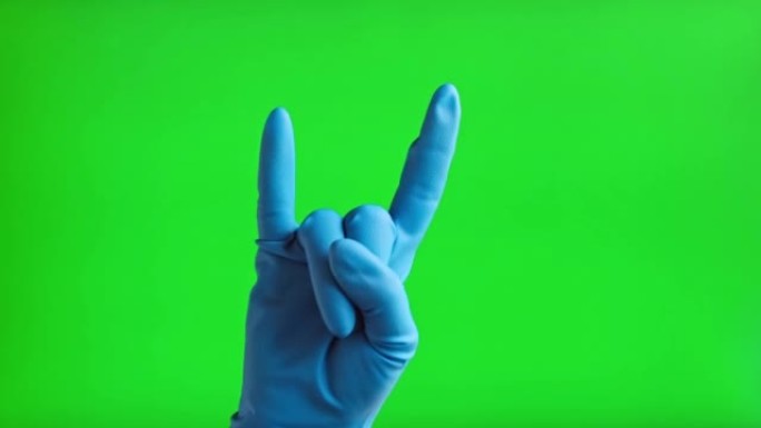 戴上医用手套，手势岩石图标隔离在绿色屏幕背景上。特写。人用蓝色手套在色度键屏幕上做摇滚手势。4k镜头