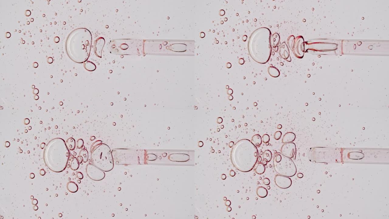 透明的粉红色化妆品凝胶液，带有分子气泡的血清油在移液器中滴落在白色背景上。天然有机化妆品、药物的宏观