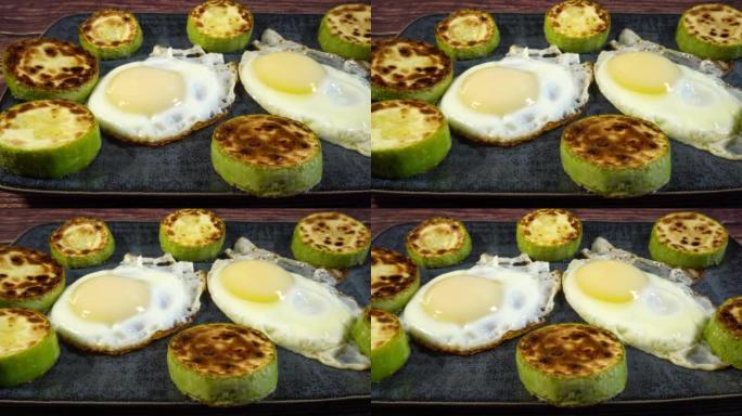 煎鸡蛋和烤西葫芦在盘子上的幻灯片。慢速微距多莉吃一顿开胃的午餐或晚餐。酮饮食减肥概念的元素。