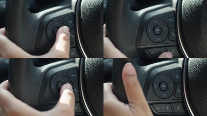 女人手指使用方向盘上的多媒体按钮来调节音量并在汽车中选择歌曲