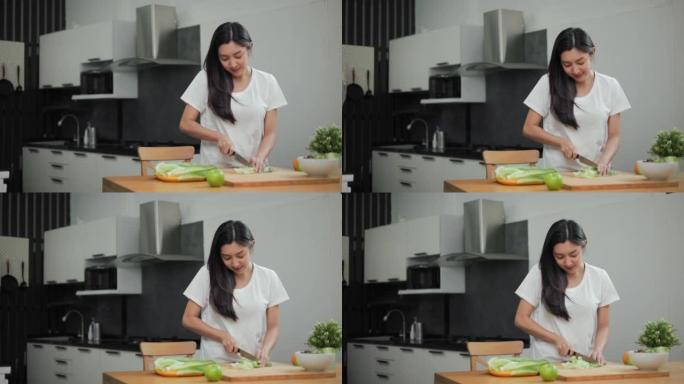 在减肥饮食中，女性在切菜板上切蔬菜和烹饪蔬菜沙拉。美丽的女人早上快乐地在厨房里做健康的早餐。饮食概念