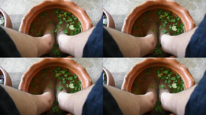 泰国男性在水疗按摩前坐在盆里用草药放松足浴