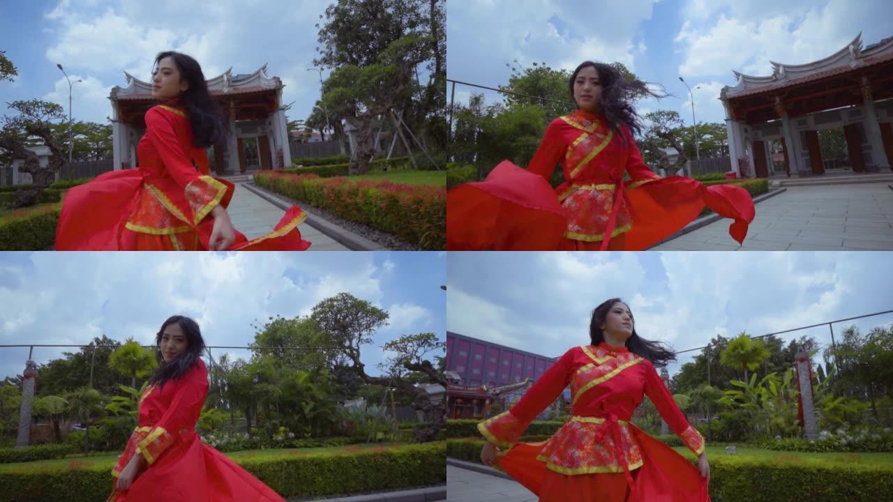 一个美丽的年轻中国女人在花园里玩红色旗袍