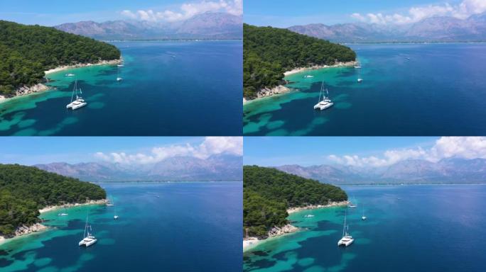 游艇、帆船和双体船停泊在清澈蓝色的地中海上异国情调的山岛附近的海湾。停泊在海岸附近的白色帆船。停泊在