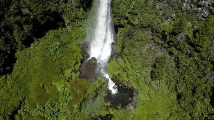 无人驾驶飞机拍摄了El salt El Leon的瀑布，周围是植被，并用彩虹鹤射击